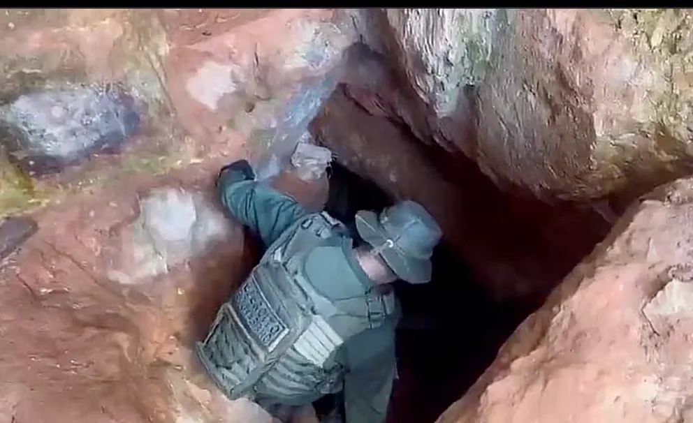Un funcionario del Ejército baja por un de las grunas o túneles de galería que abren los mineros