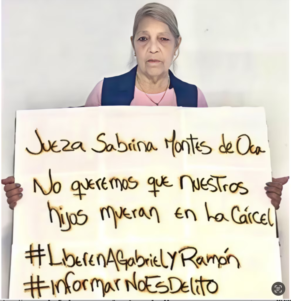 Una mujer con cabello grisáceo sostiene un cartel que pide a la Jueza Sabrina Montes de Oca la liberación de Gabriel y Ramón, afirmando que informar no es delito y que no quieren que sus hijos mueran en la cárcel