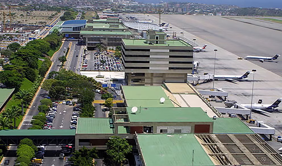 Una vista aérea del Aeropuerto Internacional Simón Bolívar, mostrando sus terminales, aviones en las puertas de embarque y en la pista, junto a zonas de estacionamiento y vegetación circundante